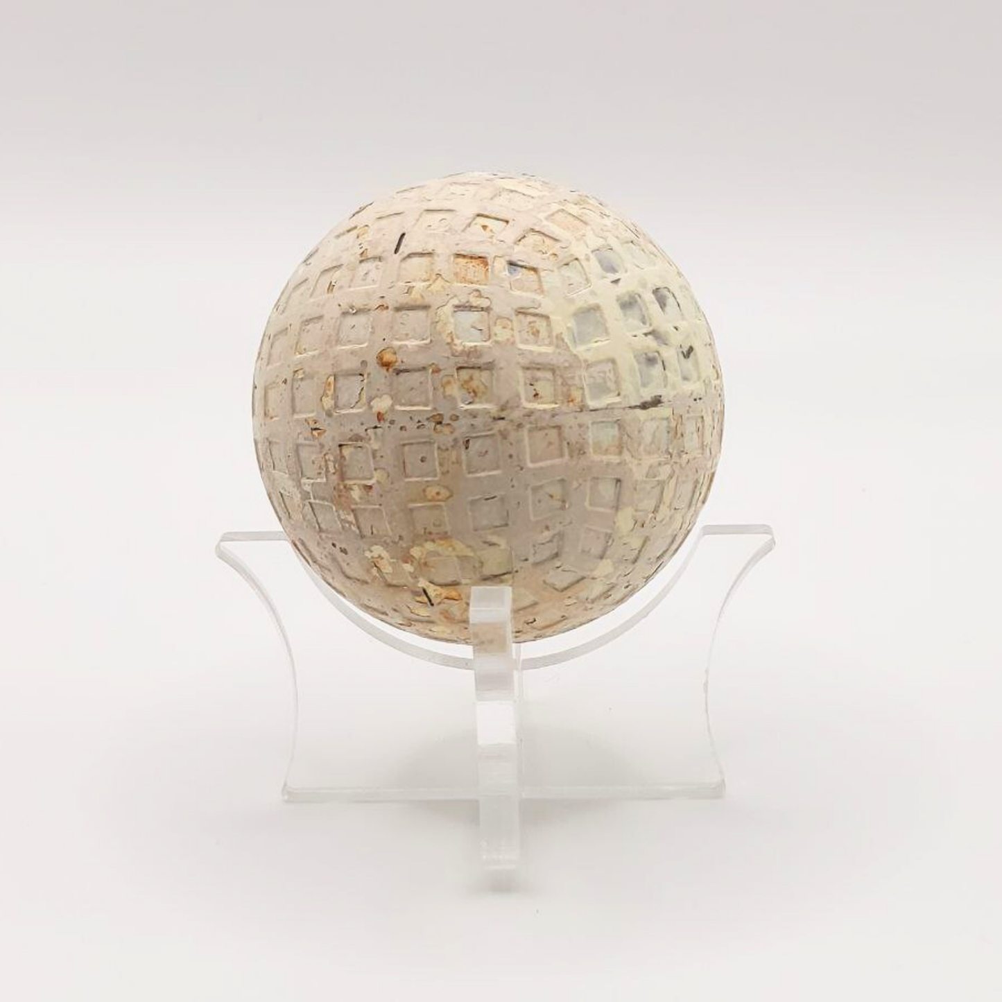 A vintage Bromford golf ball on a plastic stand against a white background.