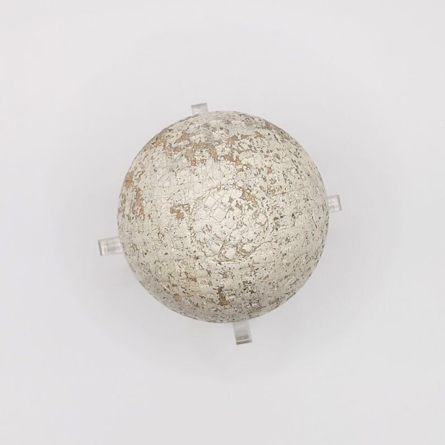 An antique golf ball made in England against a white backdrop.