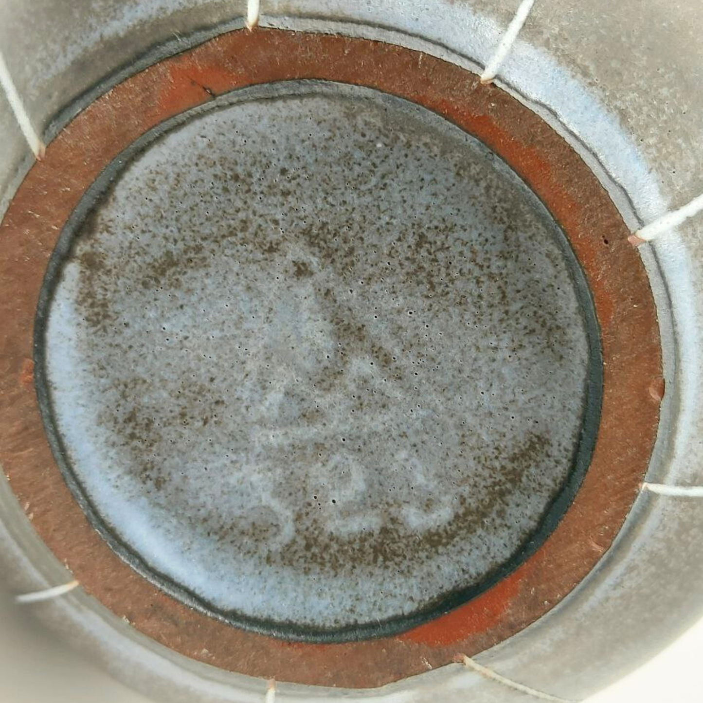 Close-up of a ceramic jug base with a brown rim and visible branding.