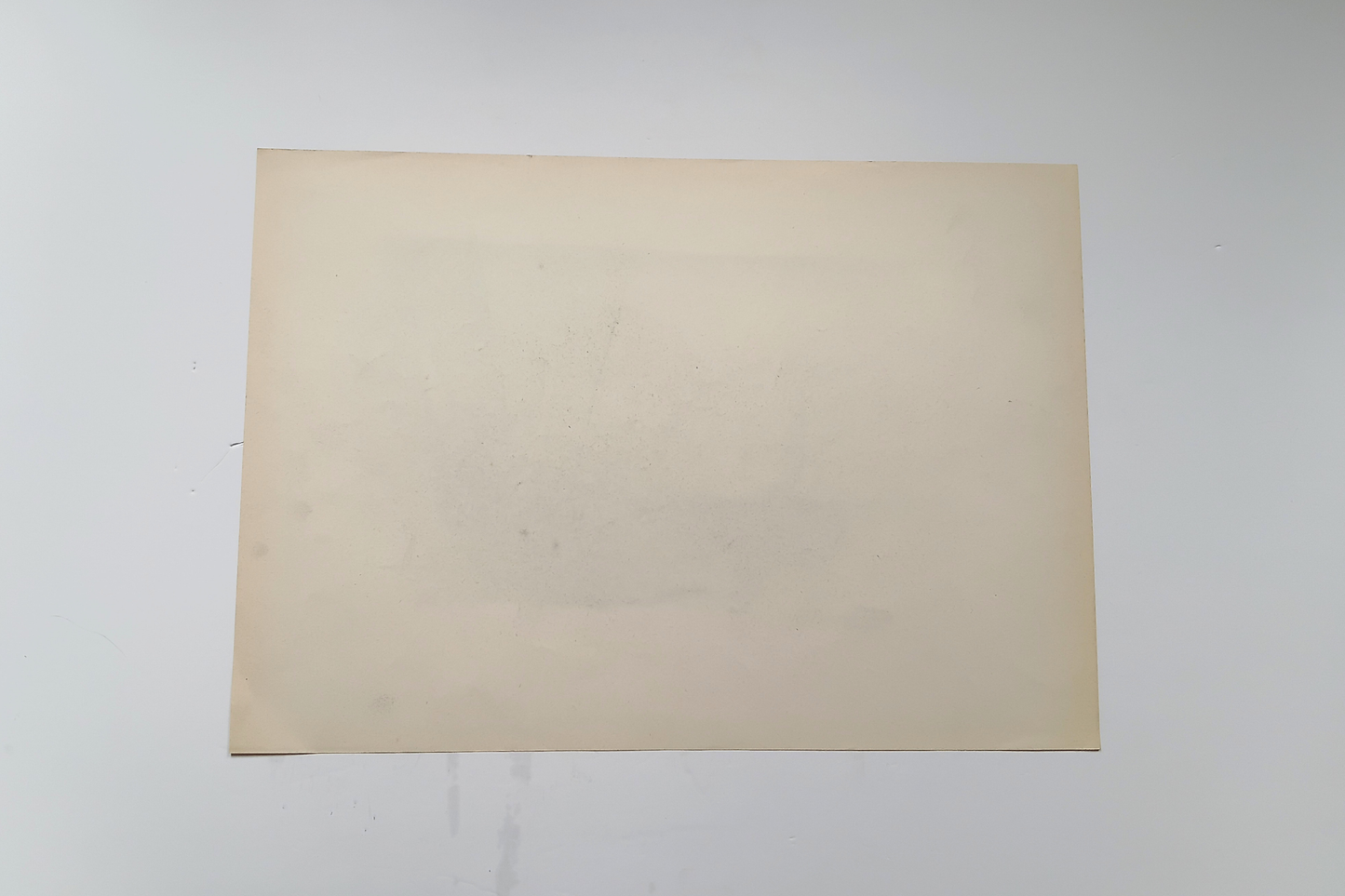 A blank, light beige rectangular sheet of paper or cardstock centered on a plain white background.