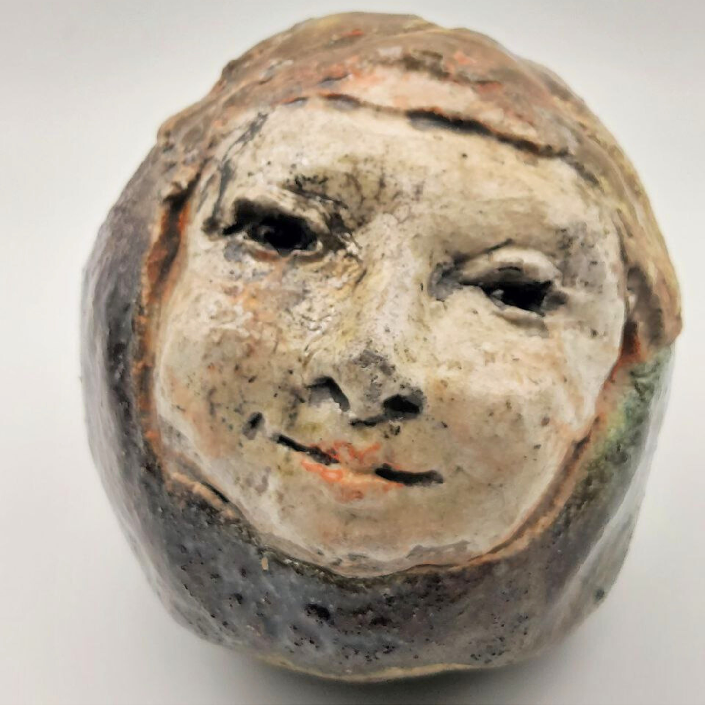 Ceramic face sculpture on a white background