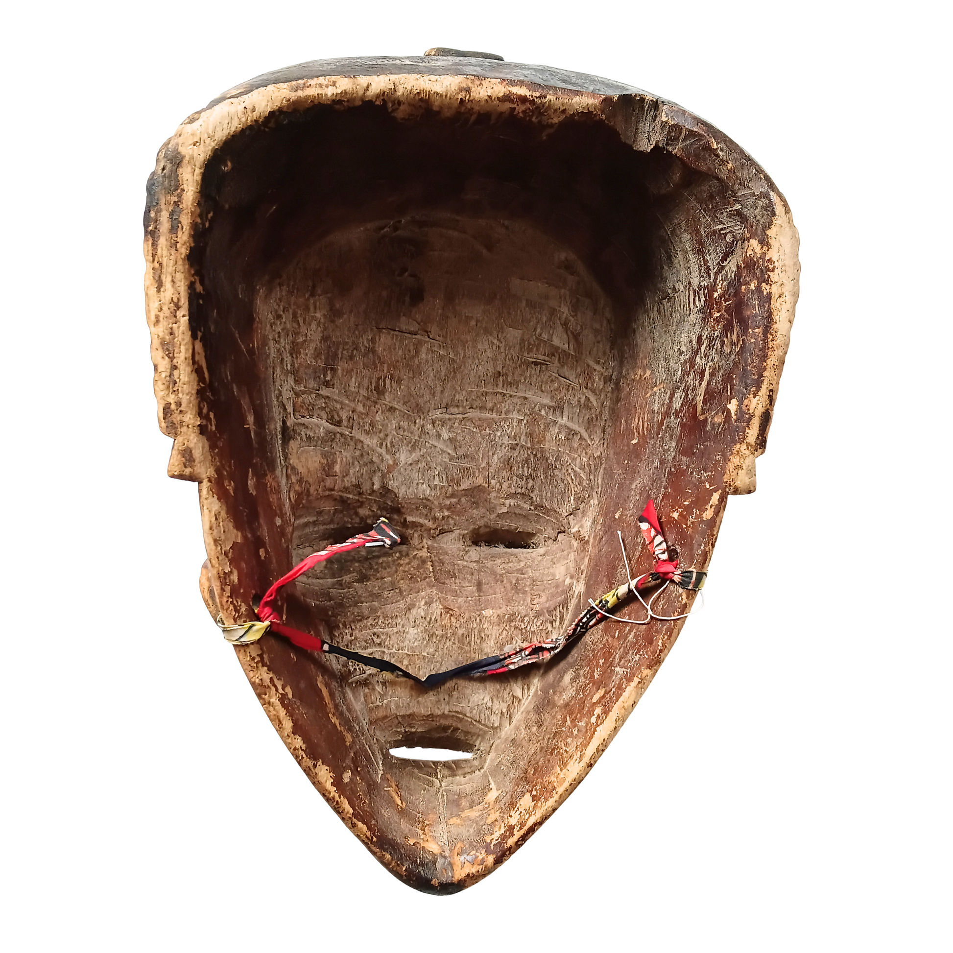 A carved wooden mask with a triangular shape, featuring cut-out facial details and red, black, and gold hanging cords, shown against a plain white background.