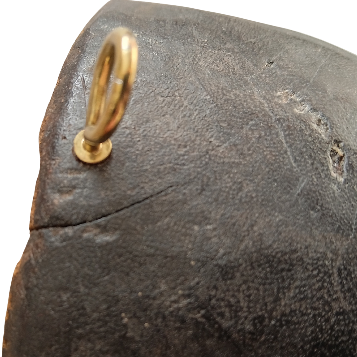 Close-up of a dark textured spoon with a brass-coloured metal loop attachment on a white background.