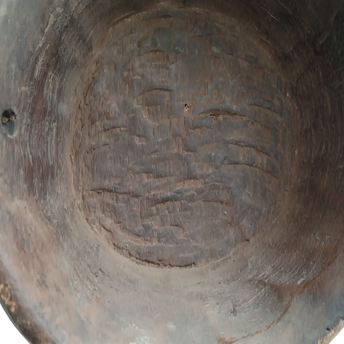Close-up of the inside of a dark brown wooden spoon, showing carved etched patterns on the bottom surface.