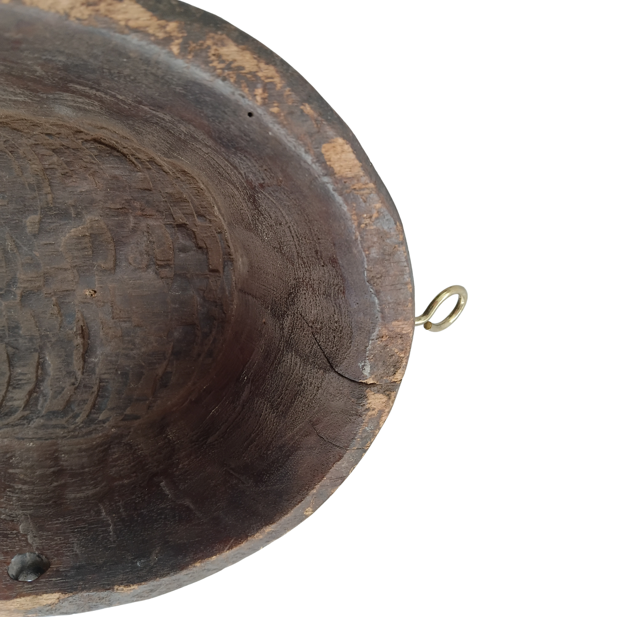Close-up of a dark brown carved wooden spoon with a small brass hanging loop on the rim, shown against a plain white background.