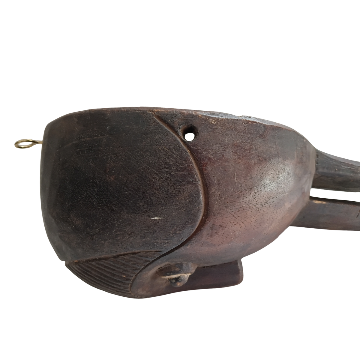 A dark carved wooden spoon with a small metal ring and hole detail, photographed against a plain white background.