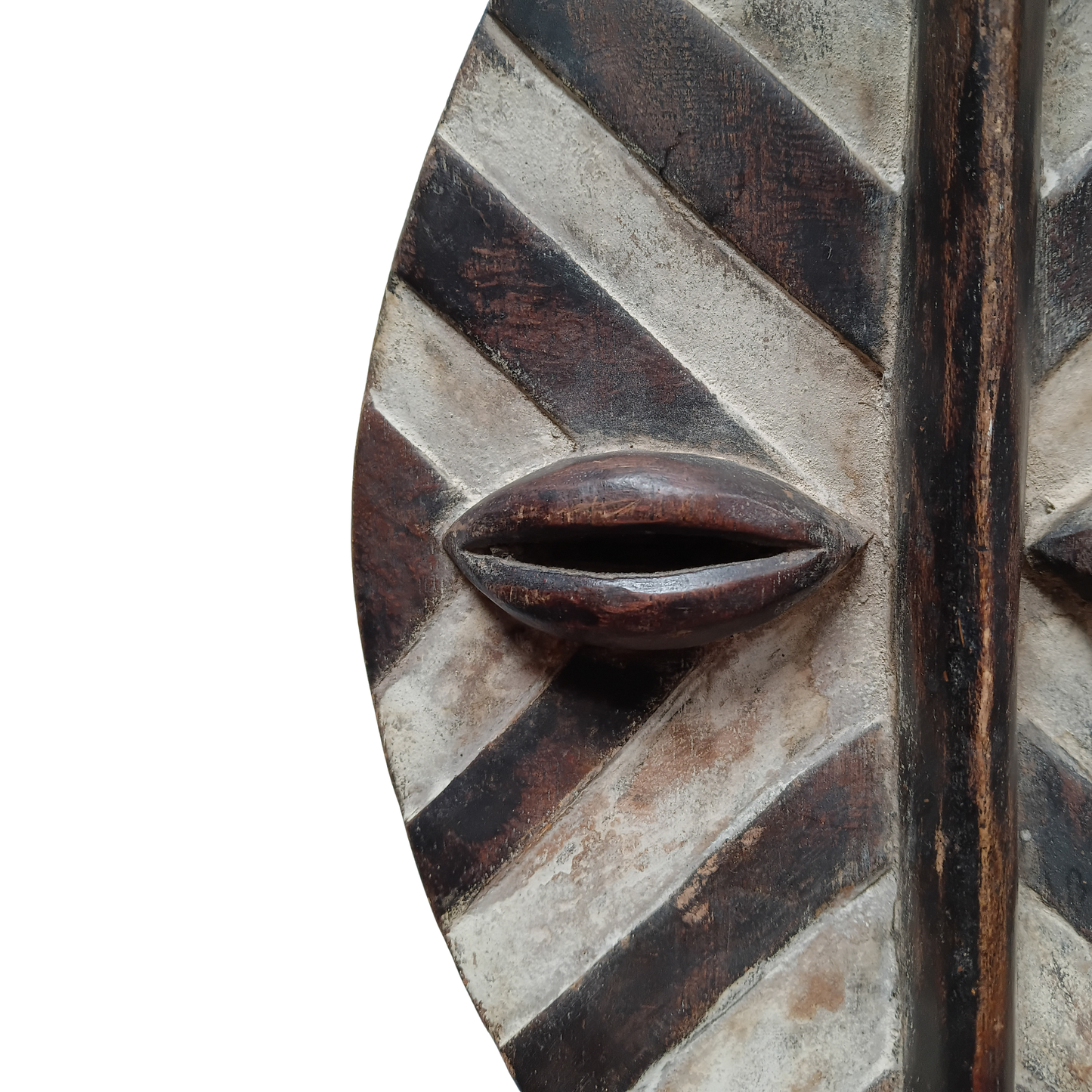 Close-up of a carved wooden mask with a central dark brown lip-like detail, set against a white background.