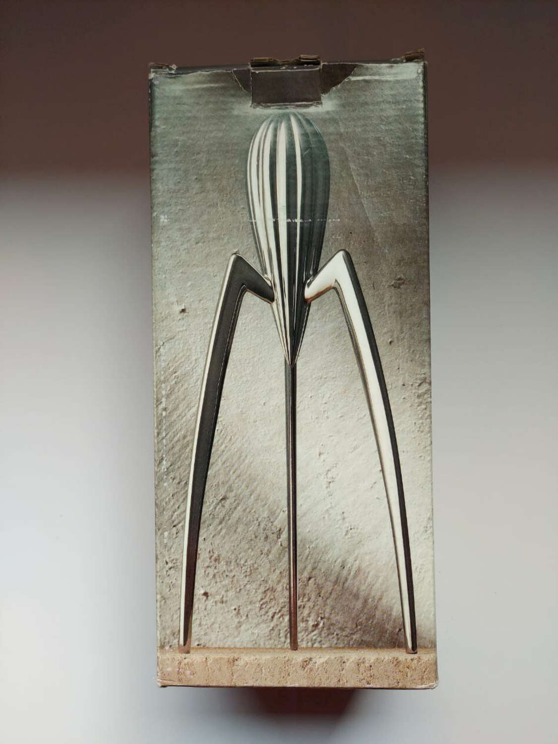 Vintage metal citrus squeezer on a textured box