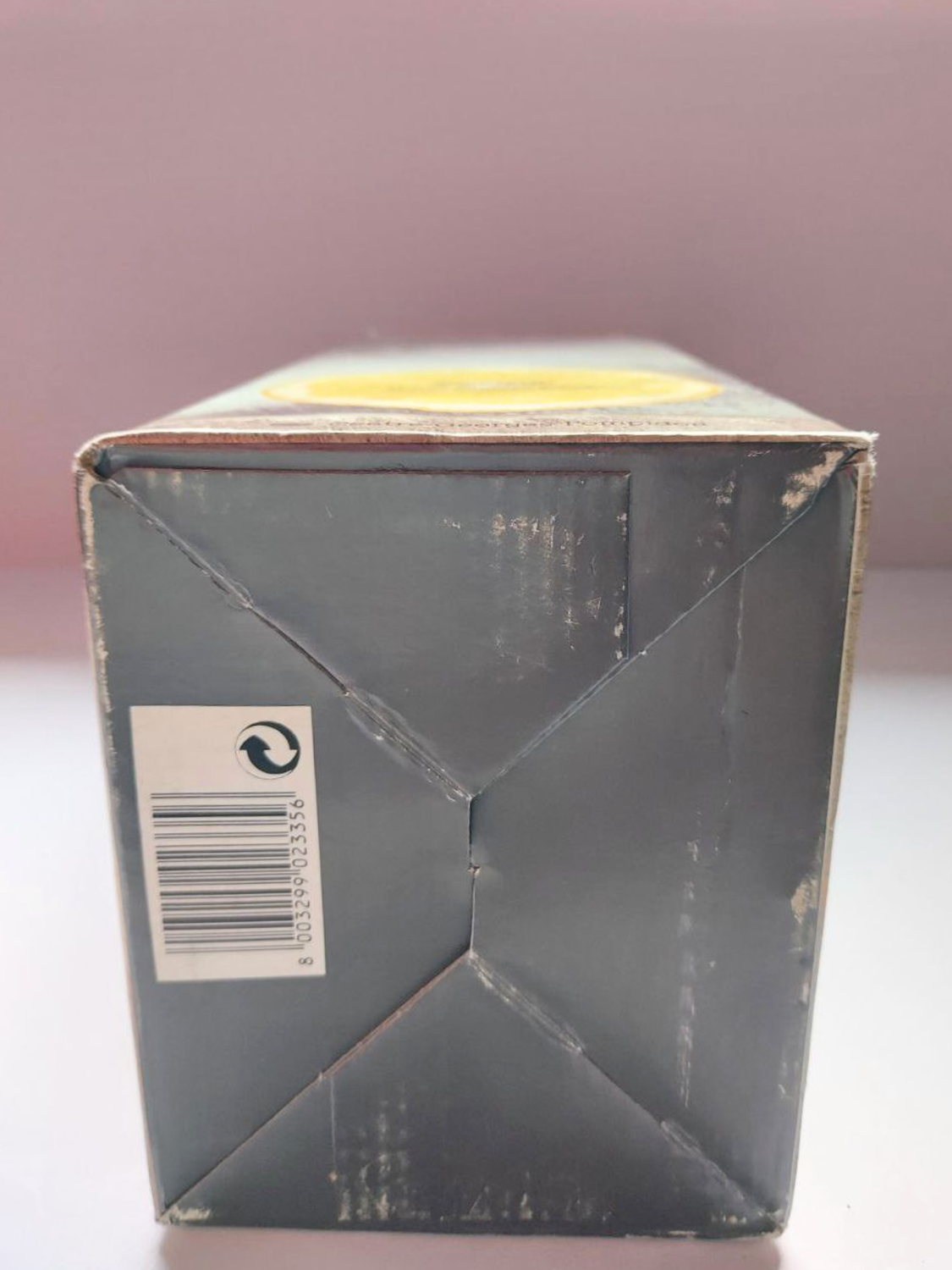 Cardboard box with a recycling symbol on a light pink background