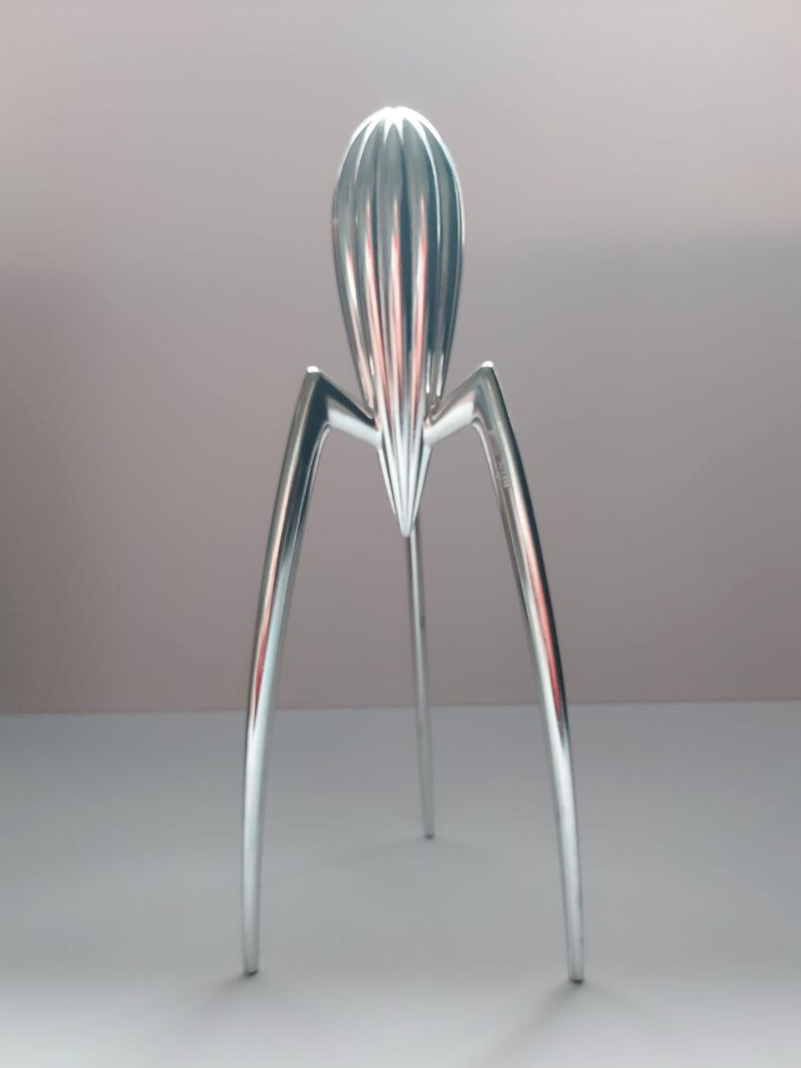 Metallic lemon squeezer on a grey background