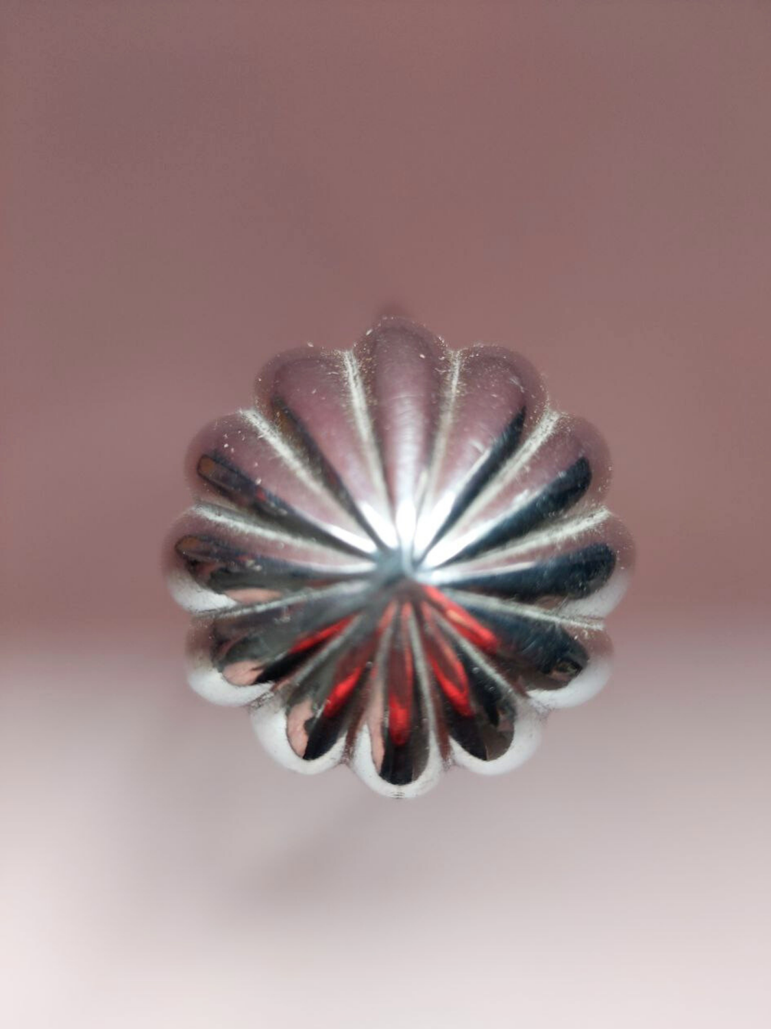 Close-up of a silver flower-shaped object on a pink background
