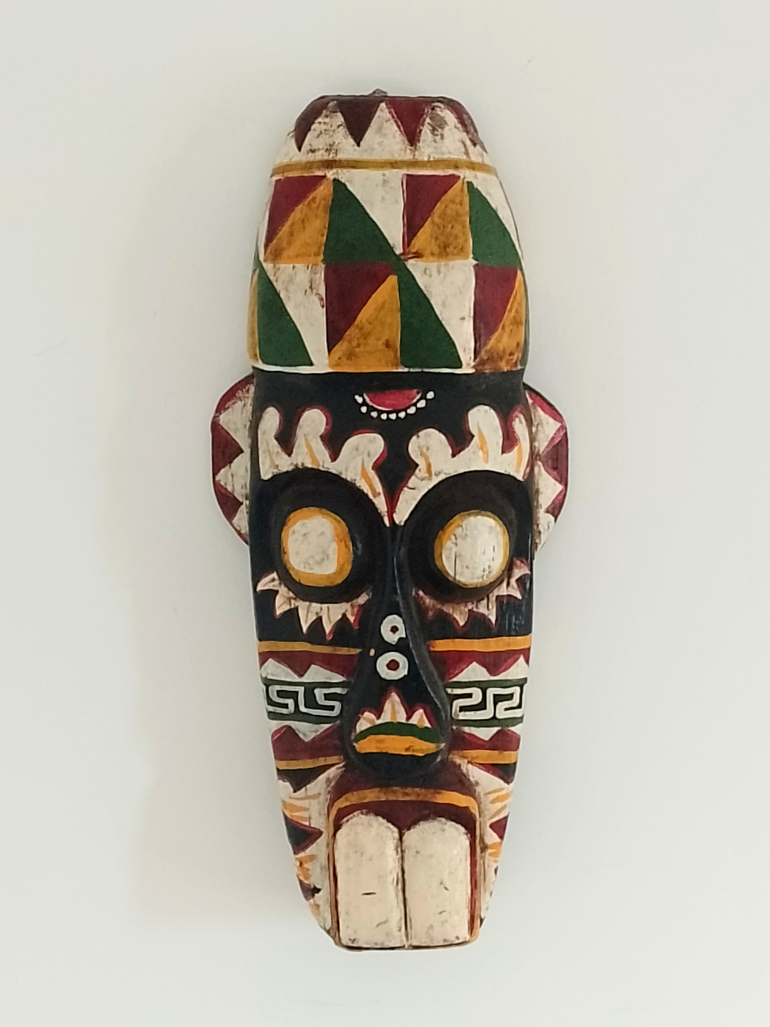 Colorful wooden mask with geometric patterns on a white background