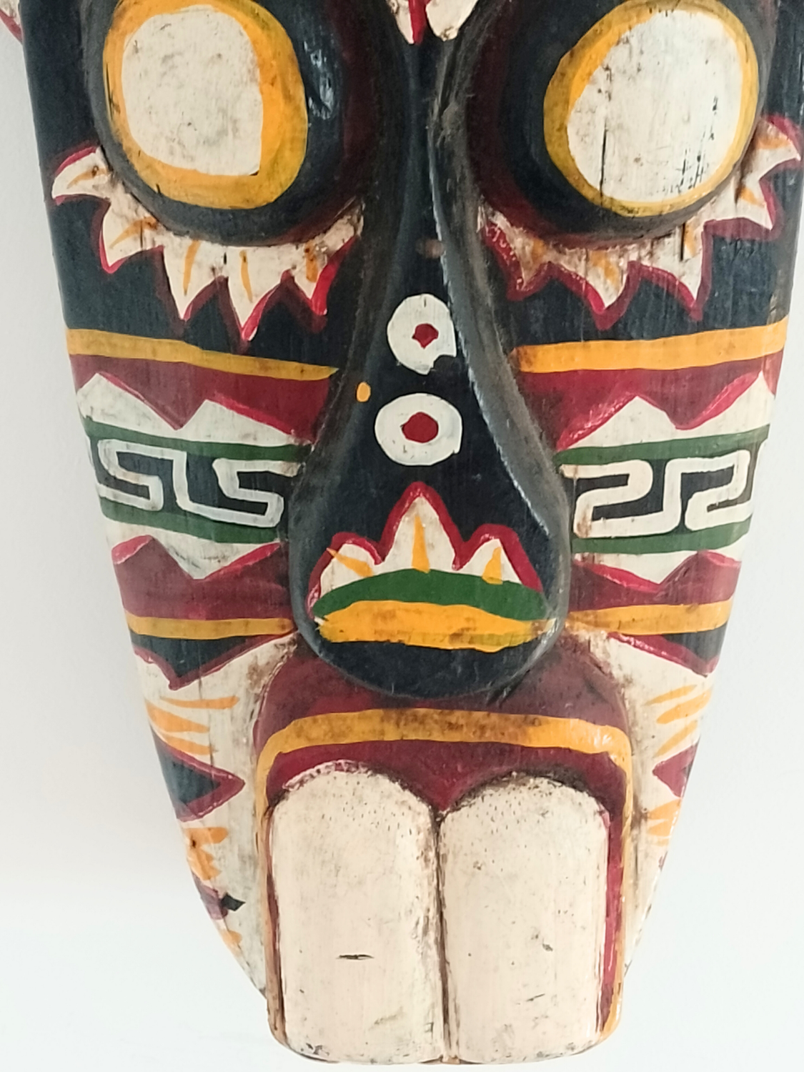 Colorful wooden mask with intricate designs on a white background