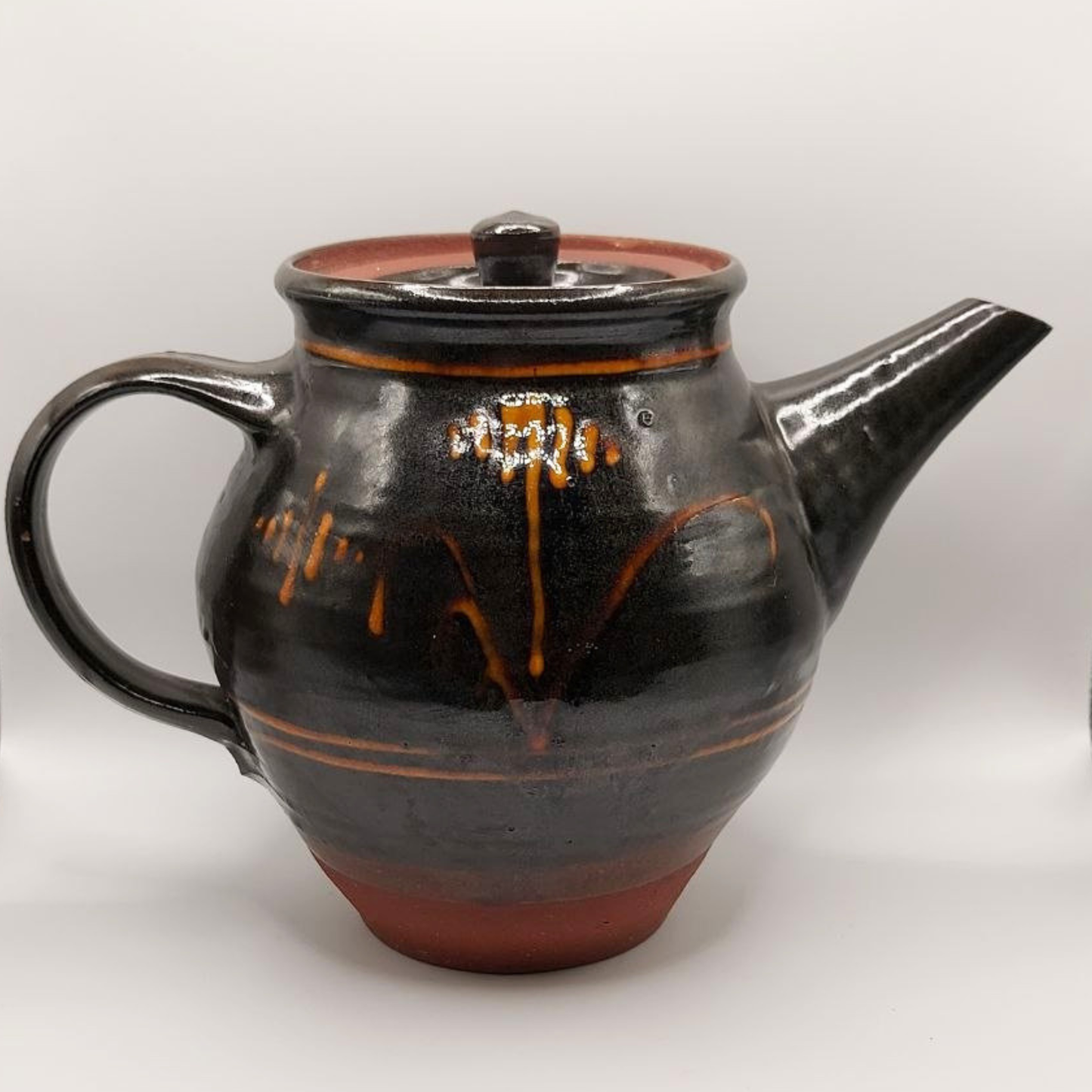 Brown ceramic teapot with yellow accents on a white background