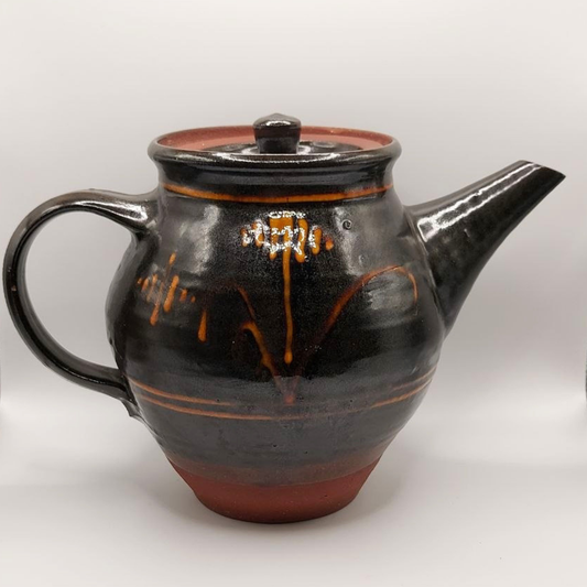 Brown ceramic teapot with yellow accents on a white background