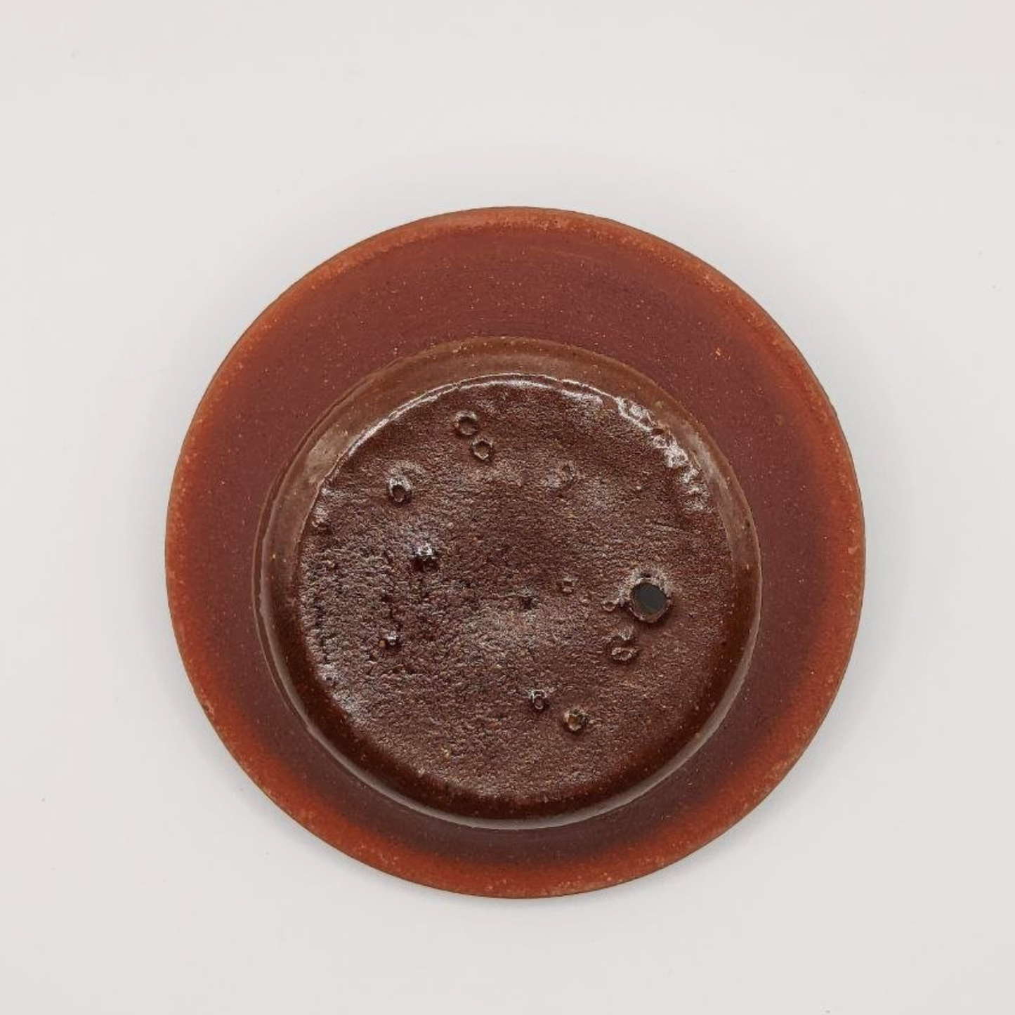 Inside of a ceramic teapot lid with a textured surface on a white background