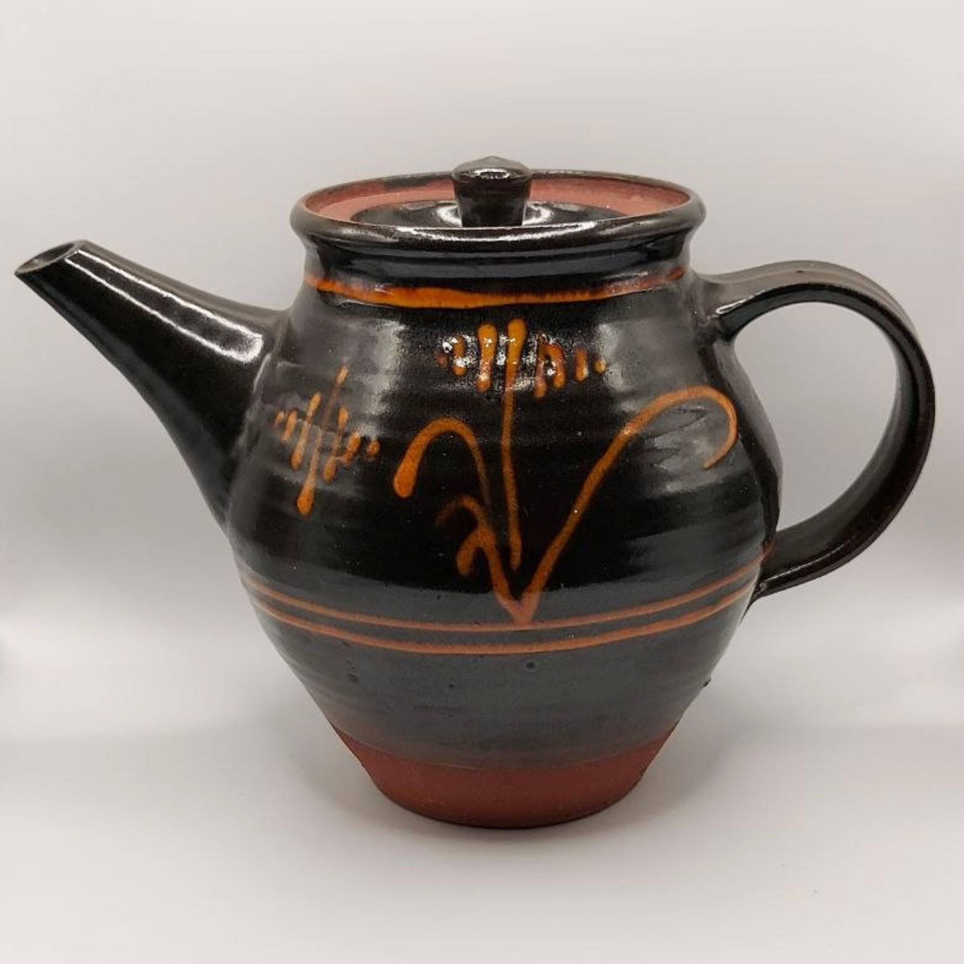 Brown ceramic teapot with orange patterns on a white background