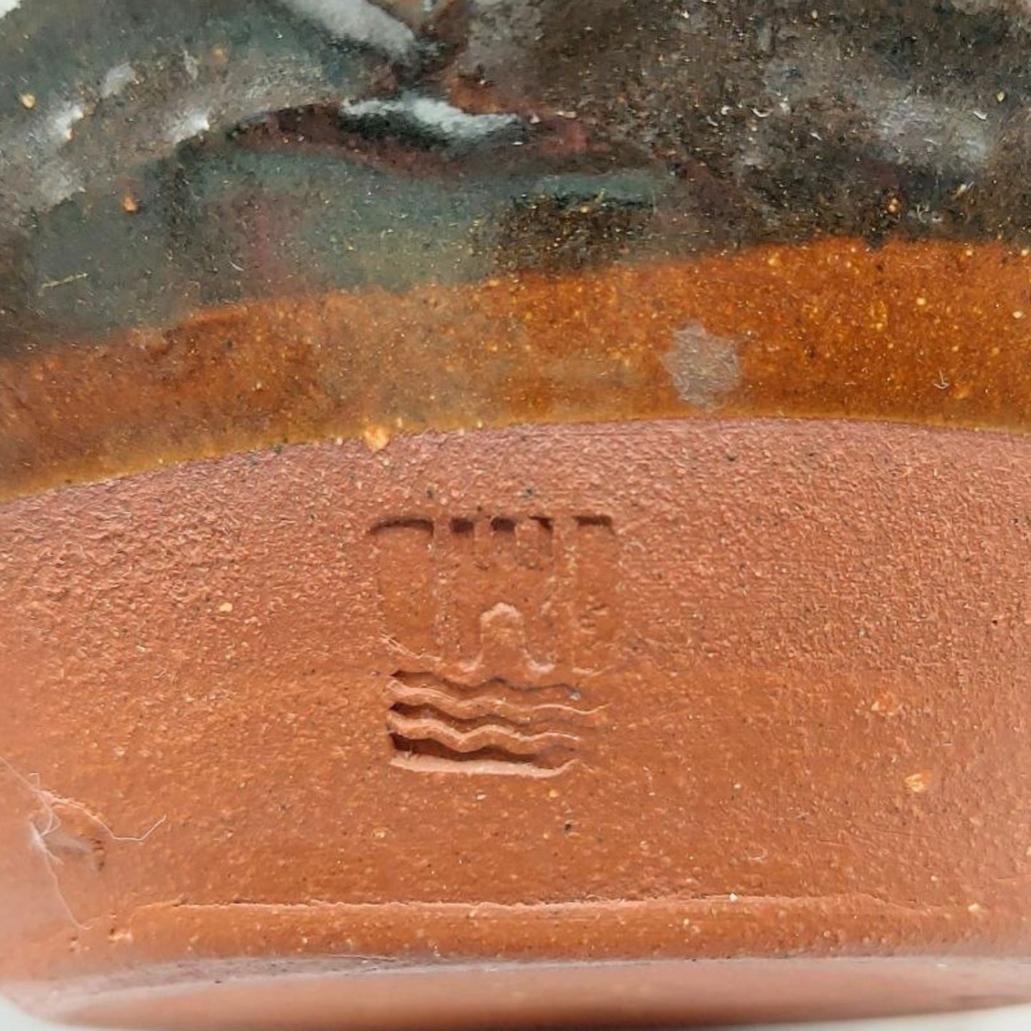 Close-up of a ceramic product with a visible brand logo on a textured surface.