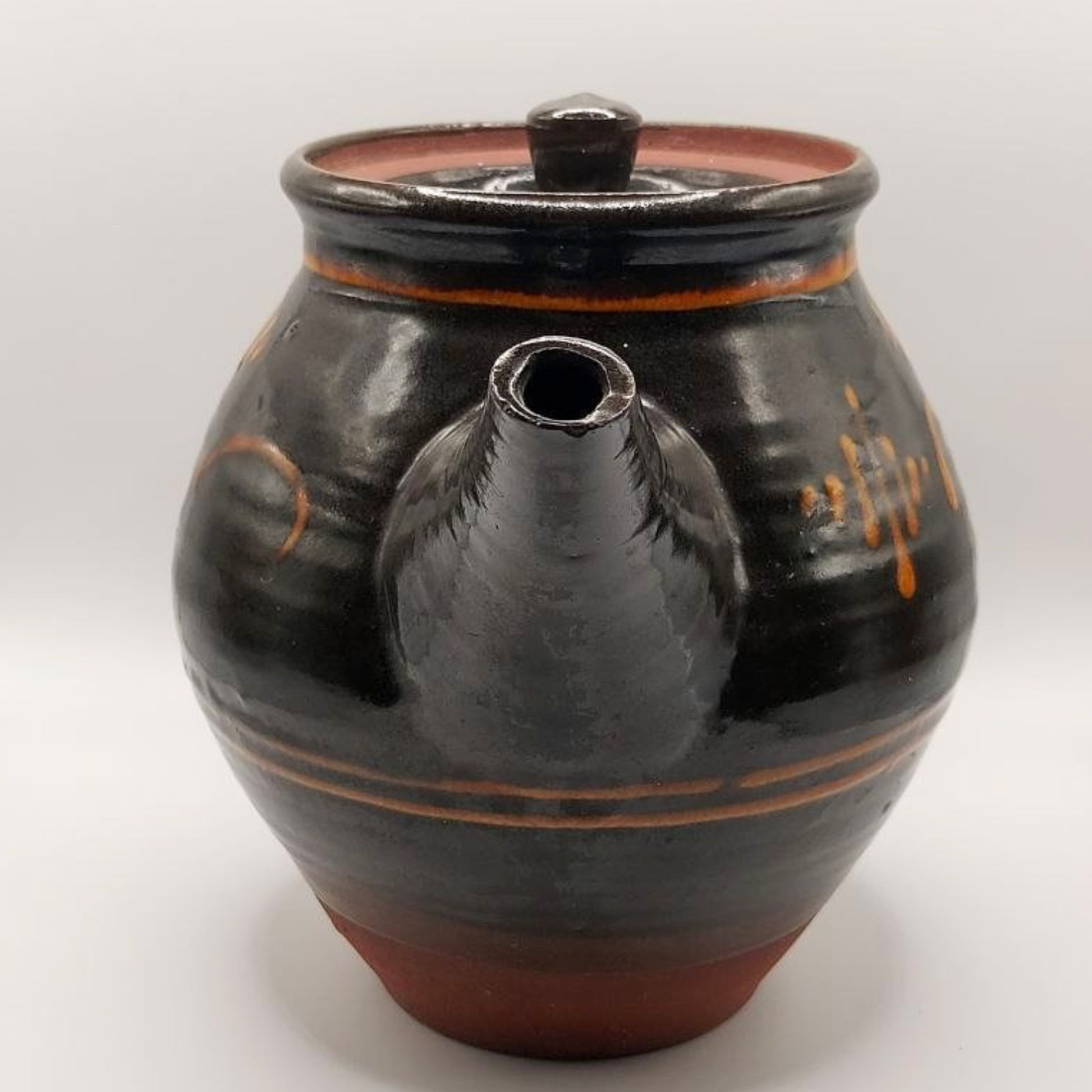 Brown ceramic teapot with orange accents on a white background