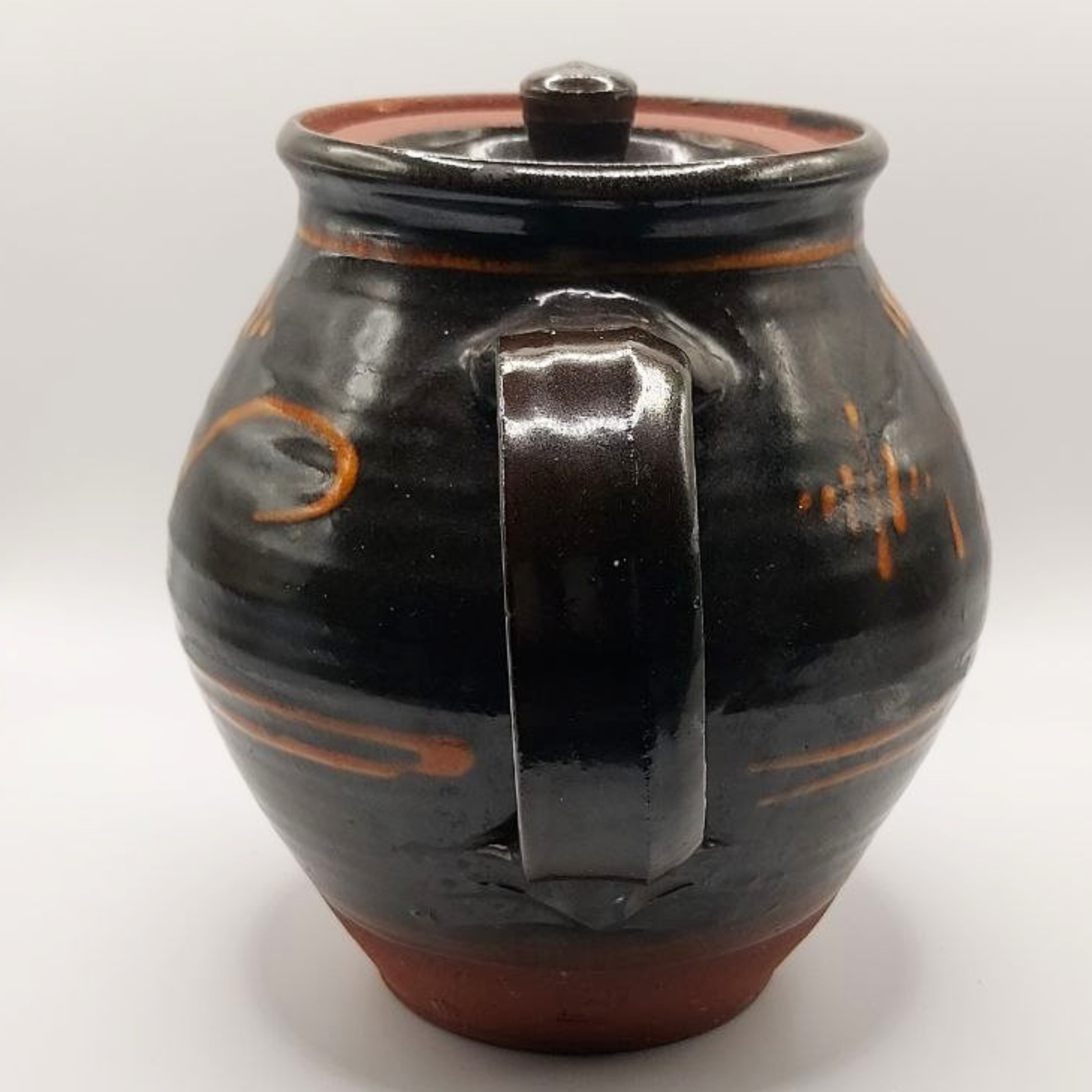 Brown ceramic teapot with orange accents on a white background