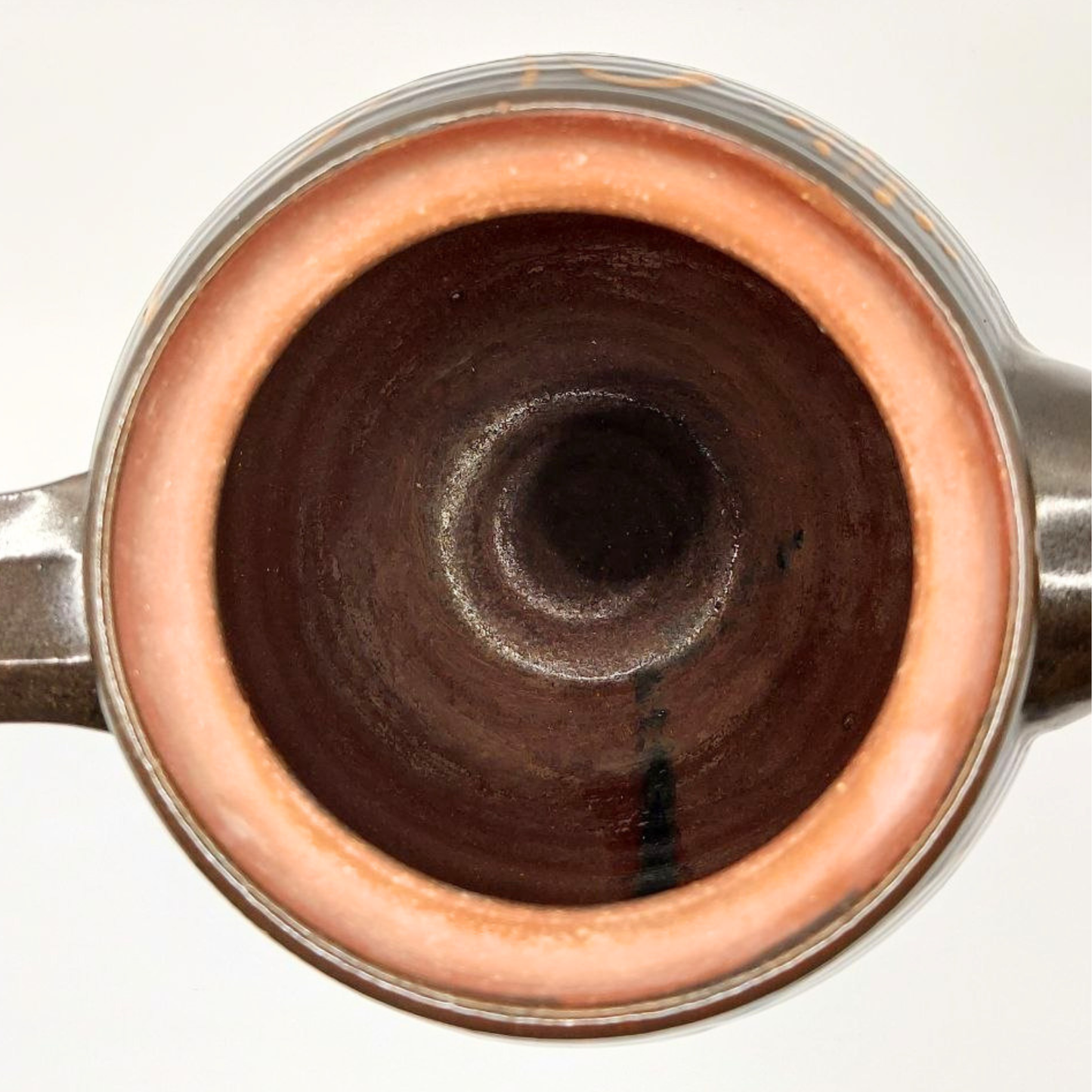 Close-up of a ceramic teapot with a dark interior on a white background