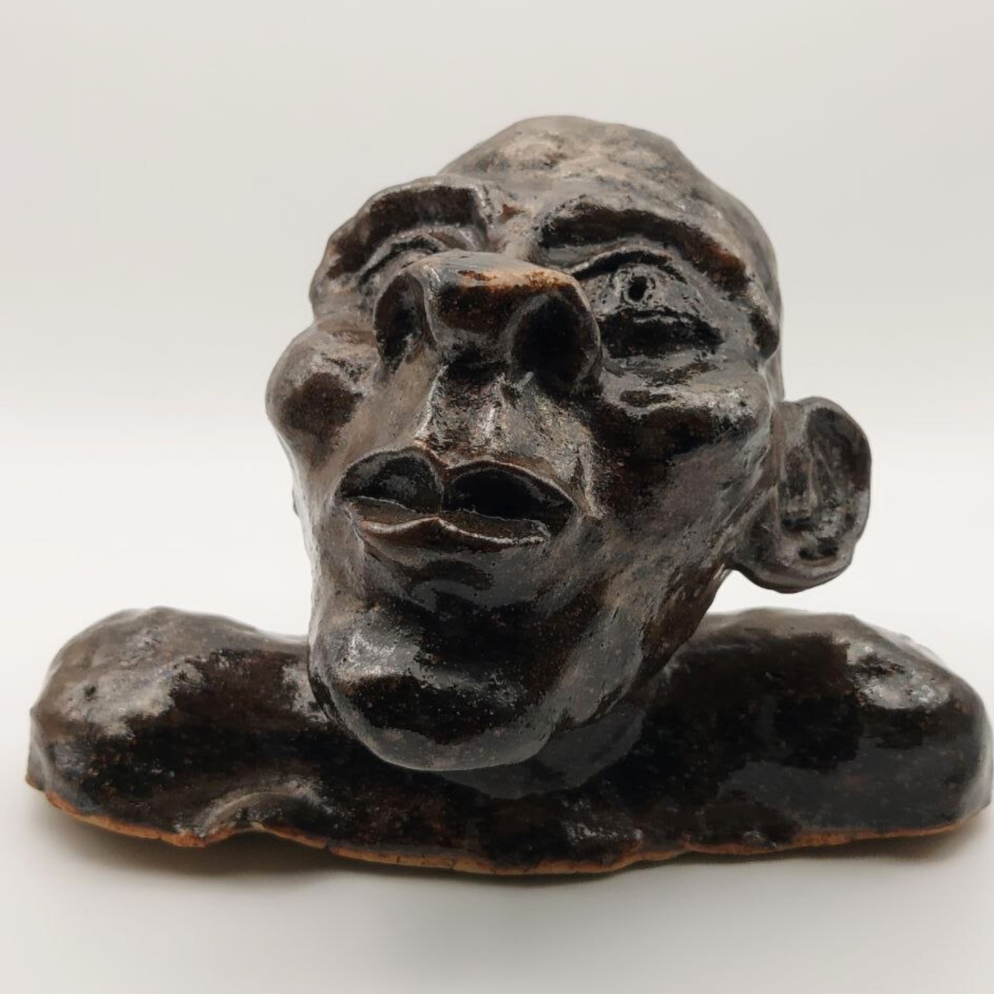 A black and brown ceramic bust on a white background