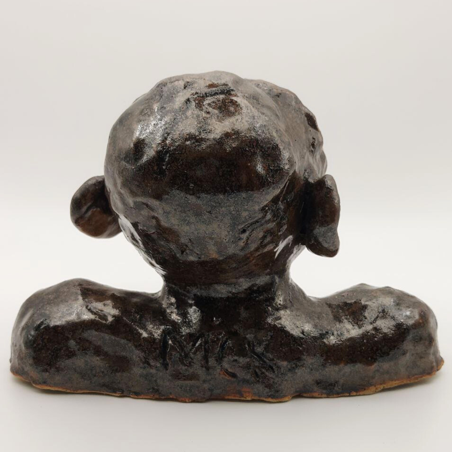 A back view of a ceramic bust on a white background