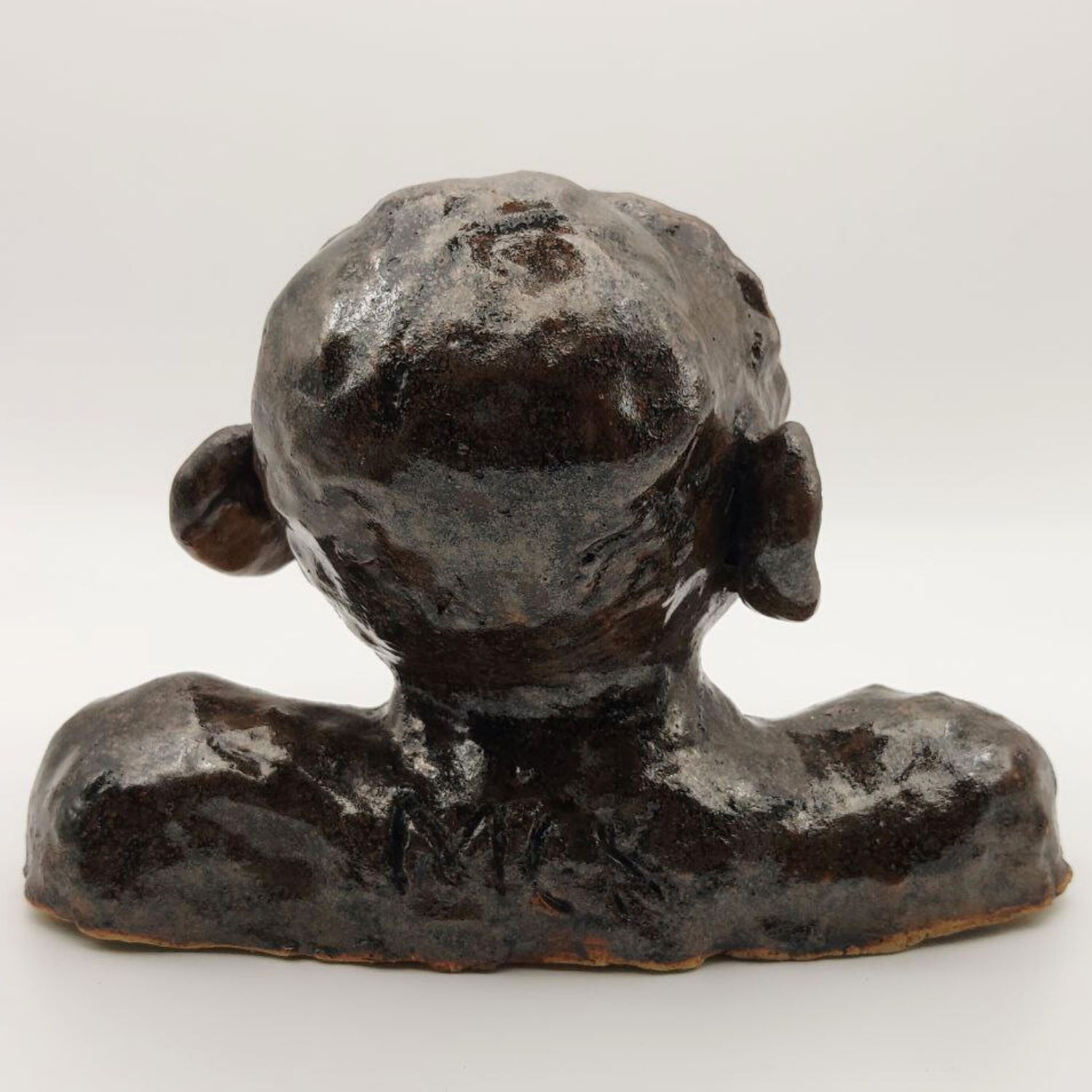 A back view of a ceramic bust on a white background