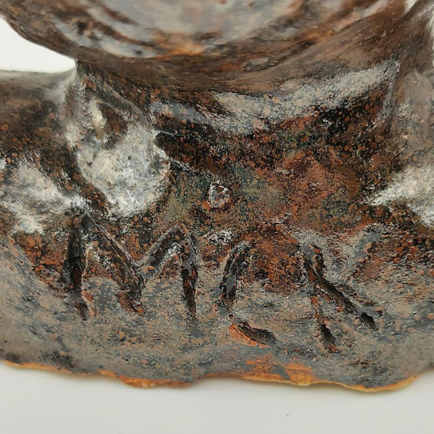 The letters "MCK" carved into a ceramic bust. 