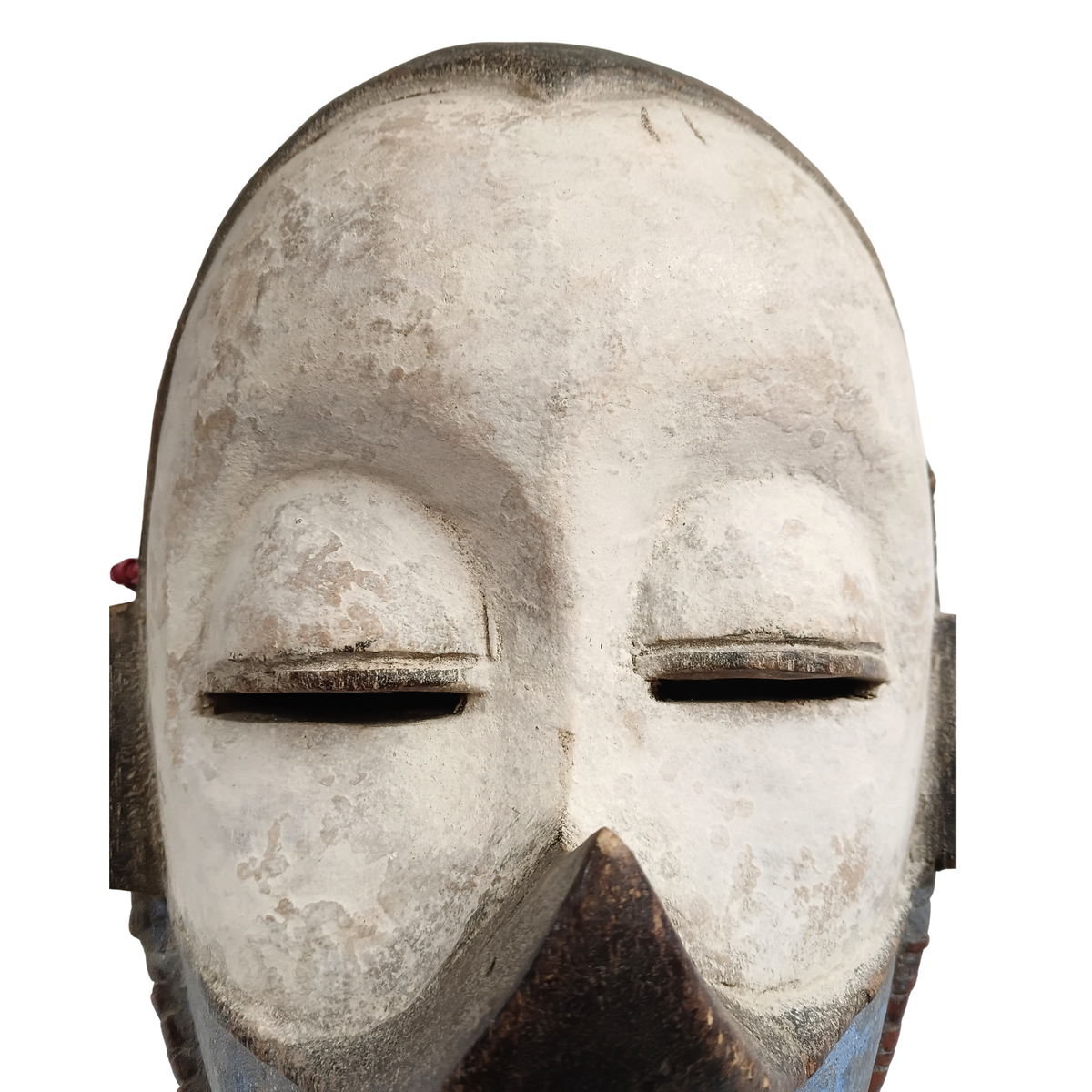 A close-up of a carved mask with closed eyes, a pointed nose, and weathered off-white and brown tones on a plain white background.