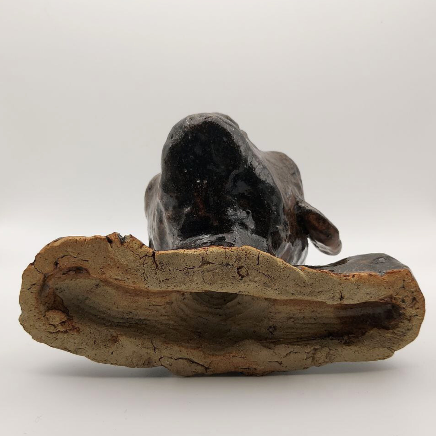 A view of the base of a ceramic bust on a white background