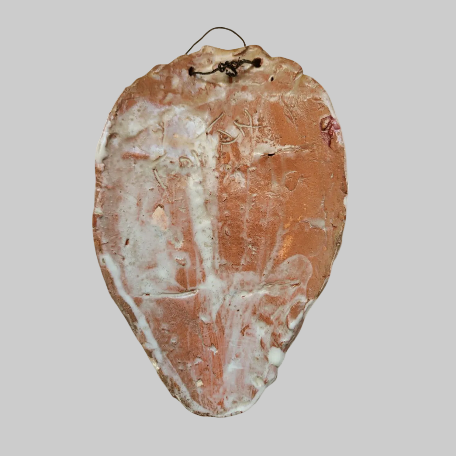 The reverse of a clay mask with a signature on it. 