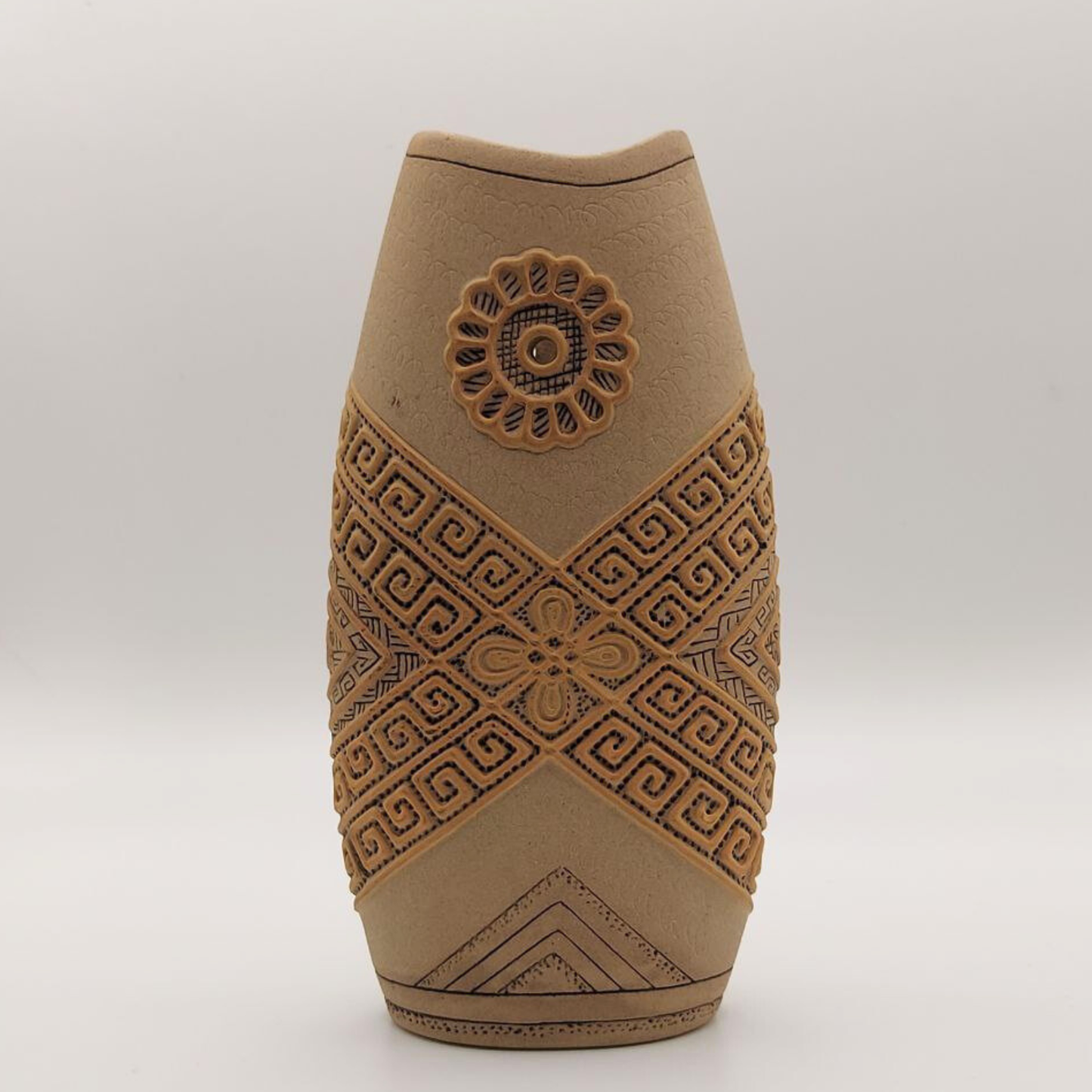 Decorative brown vase with intricate patterns on a white background