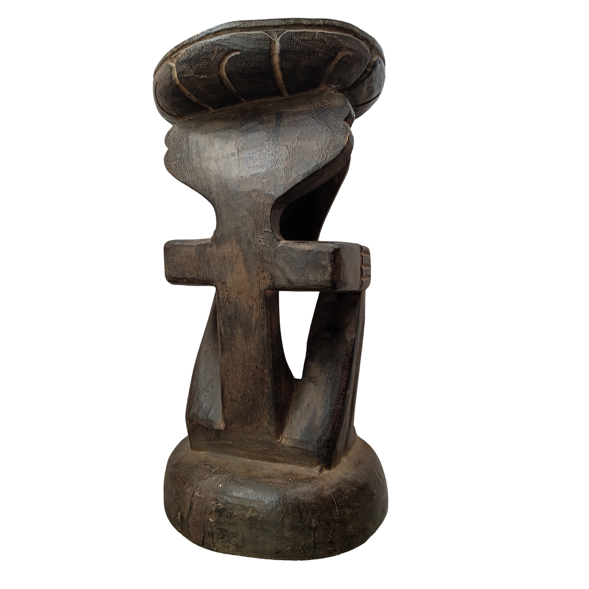 A dark carved wooden stool with a wide, tiered seat and a thick, sculptural base, shown against a plain white background.