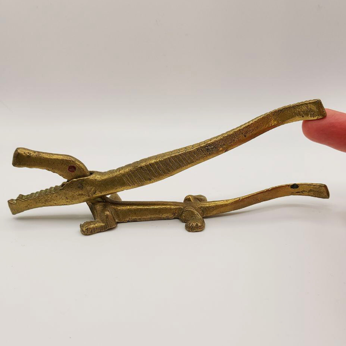 Brass nutcracker held by a hand against a white background
