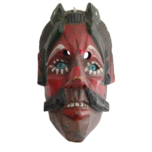 A carved wooden mask with a red face, black hair and mustache, white eye details, and blue painted eyes, shown against a plain white background.