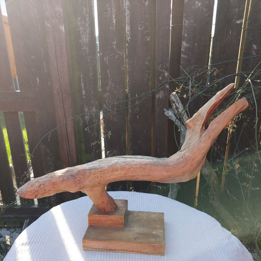 Driftwood sculpture on a table against the backdrop of a wooden fence. 