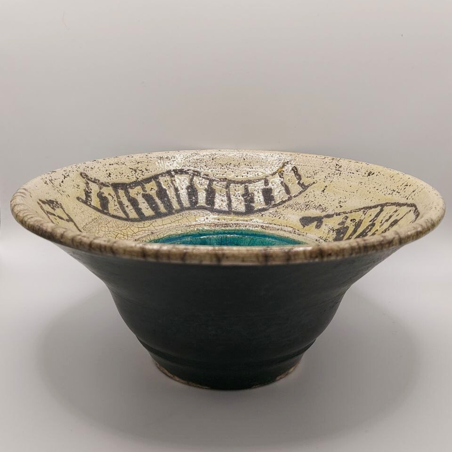 Earthenware pottery bowl with decorative rim on a gray background