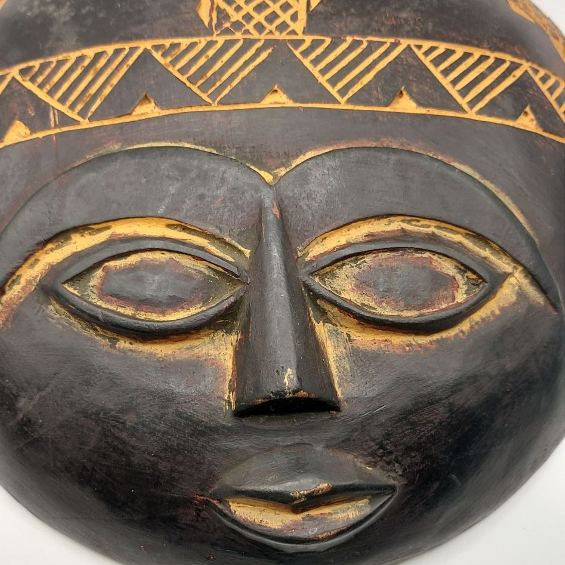 Black mask with gold geometric patterns on a white background