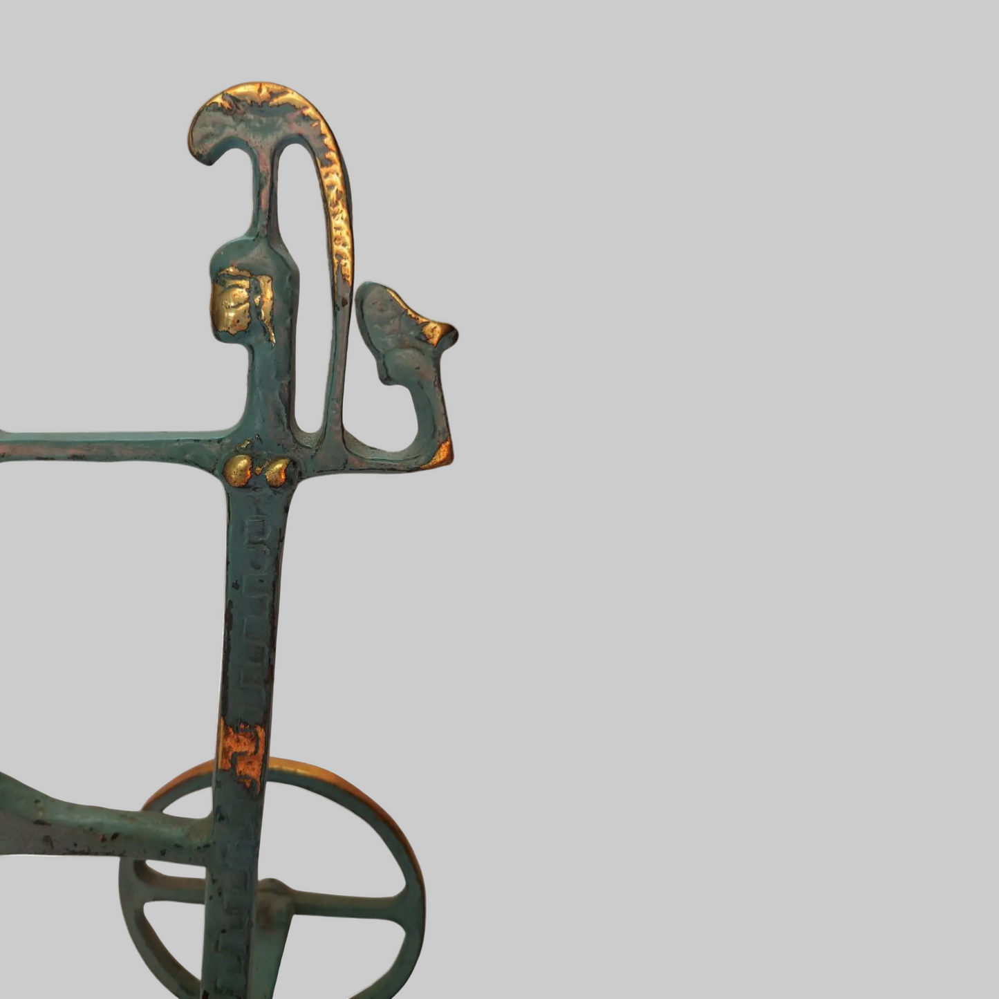 Decorative metal object with green patina and gold accents on a white background
