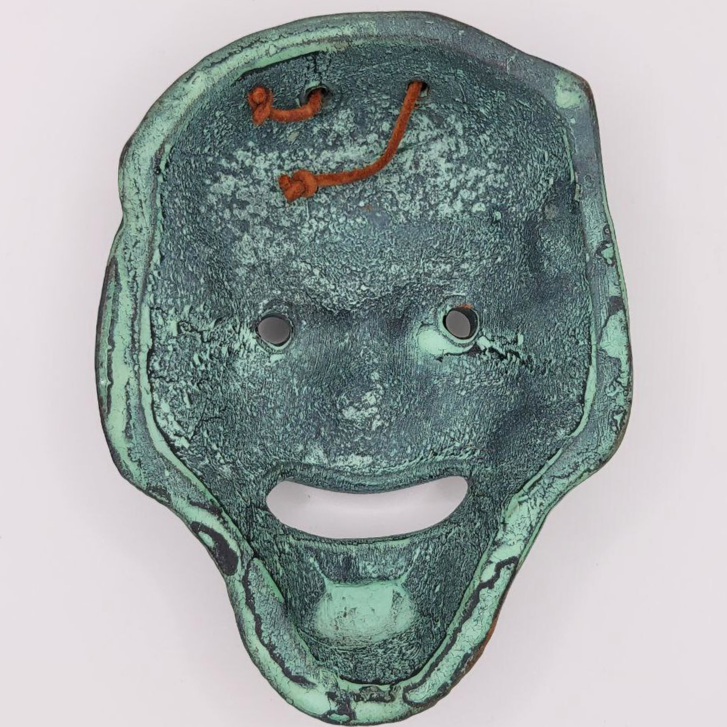 Bronze style mask with a textured surface on a white background