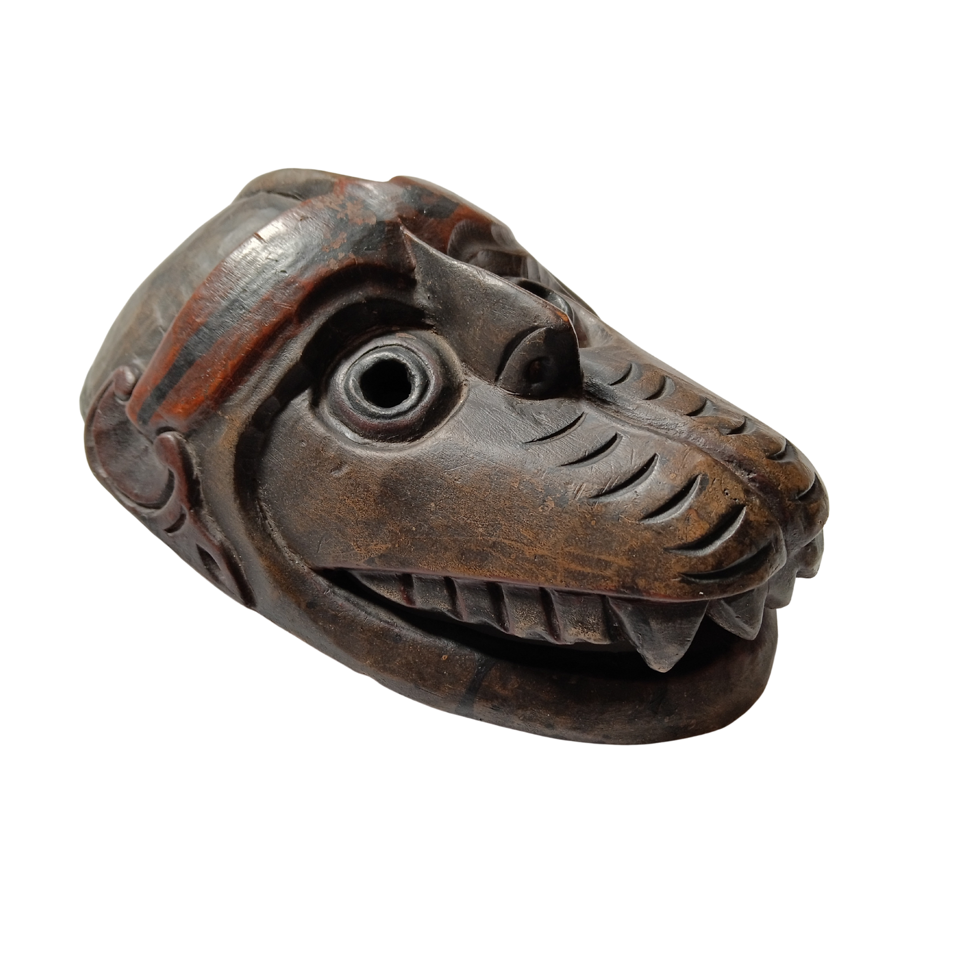 A carved wooden mask featuring detailed facial features, carved teeth, and reddish-brown painted accents, shown on a plain white background.