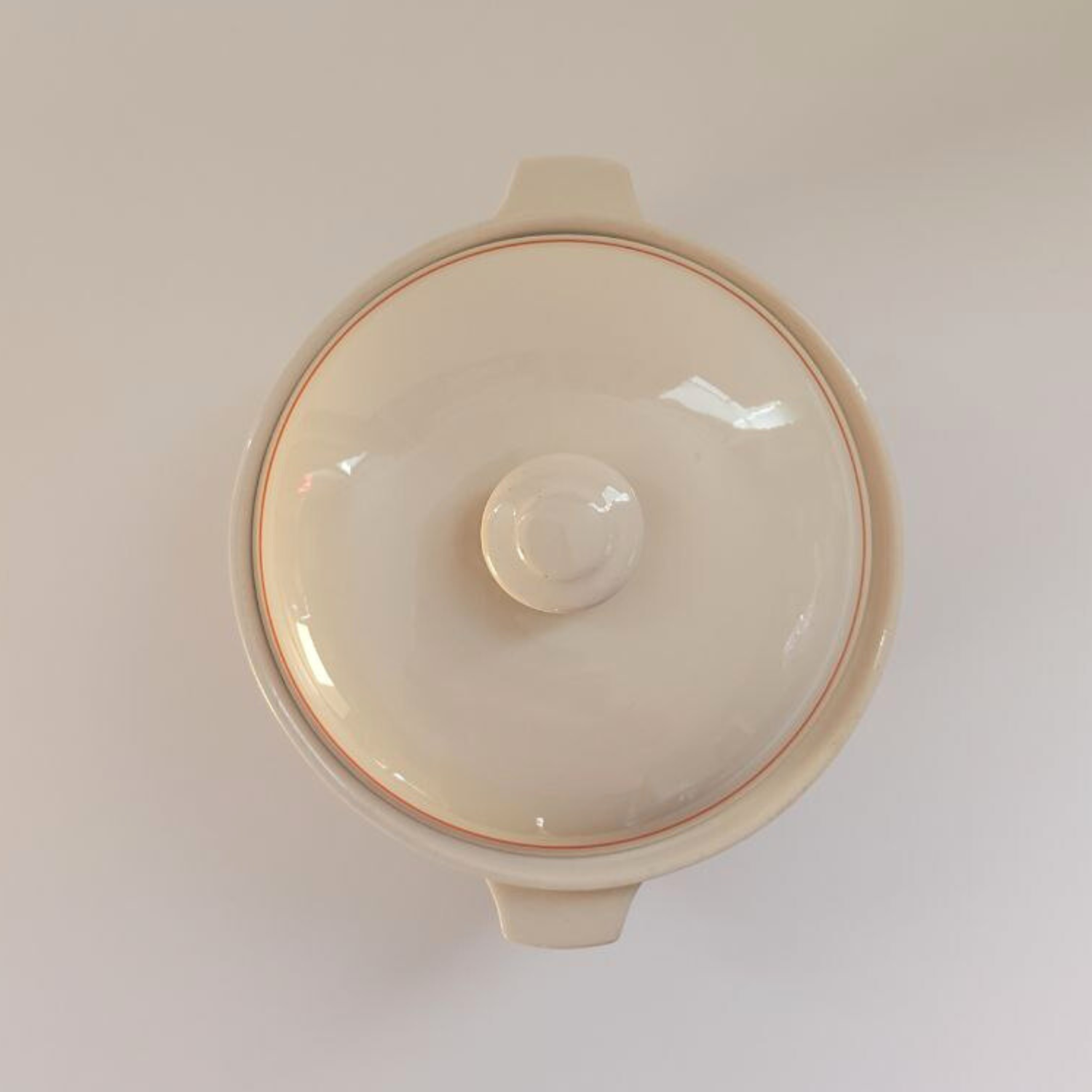 Beige ceramic dish with a lid on a white background