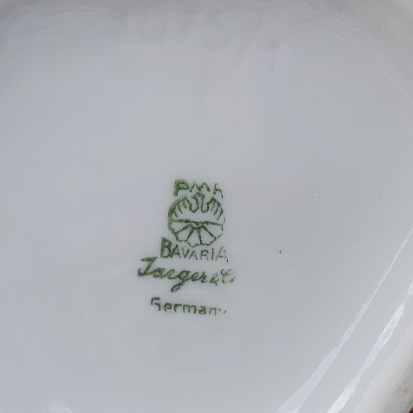 Close-up of a white vase base with green text and logo, indicating 'Jaeger', 'Bavaria' and 'German'.
