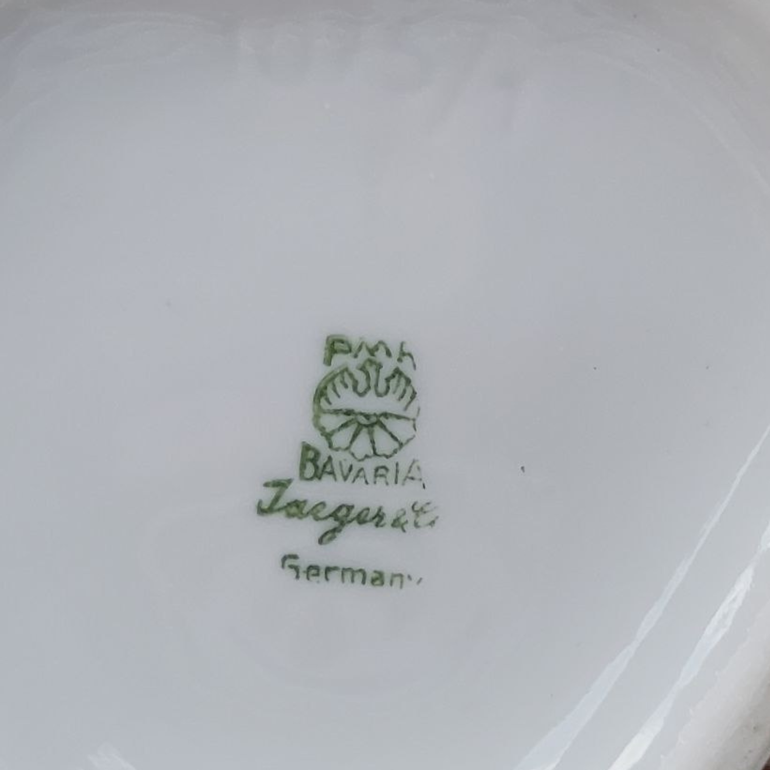 Close-up of a white vase base with green text and logo, indicating 'Jaeger', 'Bavaria' and 'German'.