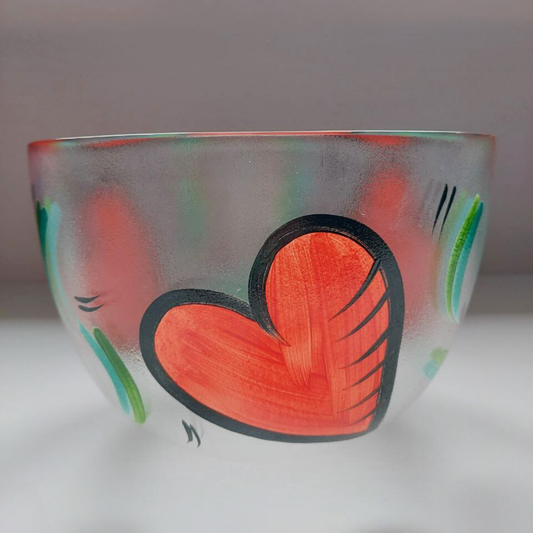 A glass bowl with a red heart on the side. 