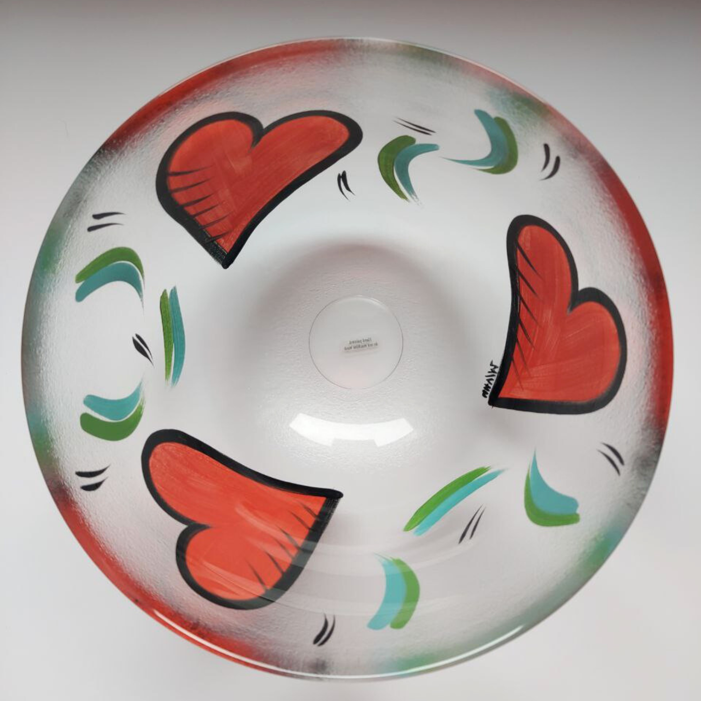 Decorative bowl with red hearts and green abstract designs on a white background