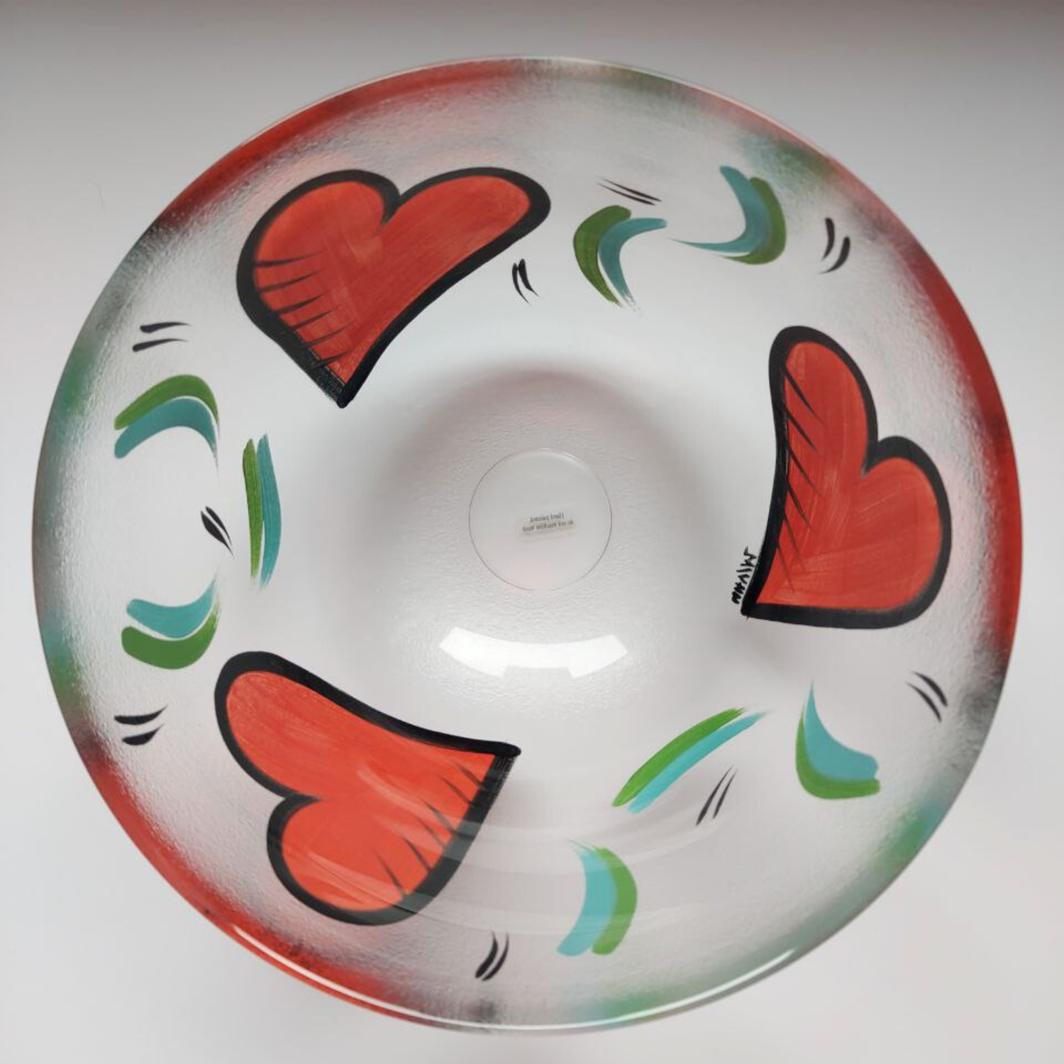 Decorative bowl with red hearts and green abstract designs on a white background
