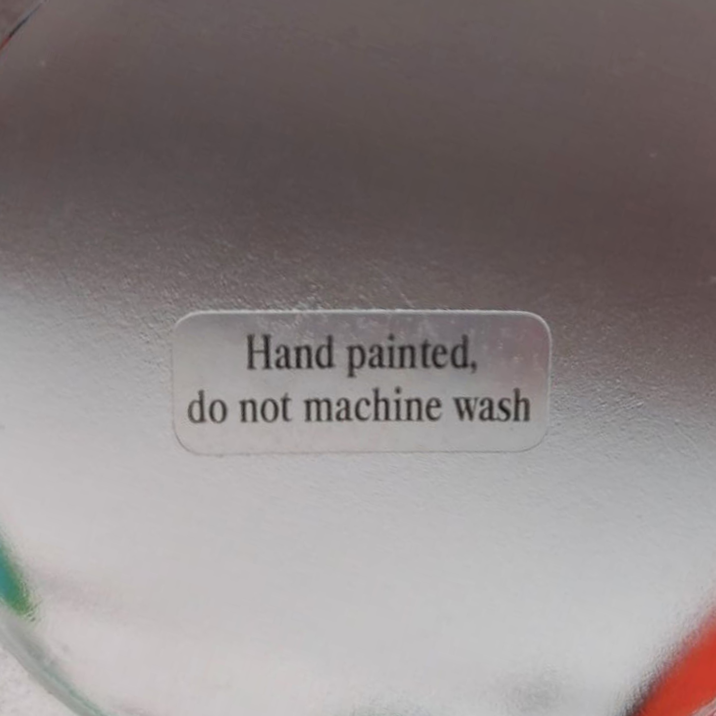 Text label on a textured surface indicating 'Hand painted, do not machine wash'.