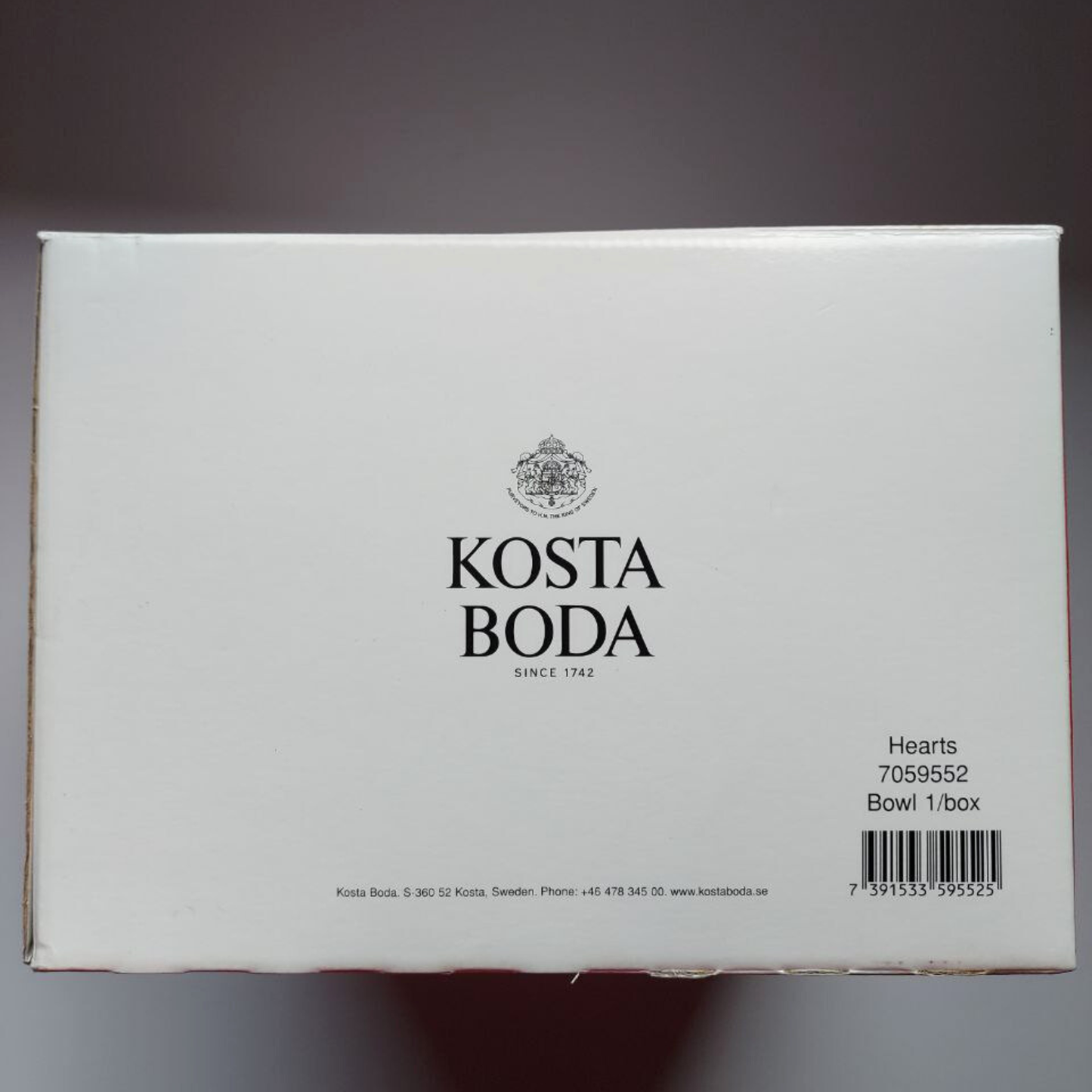 Kosta Boda product packaging with branding and product details on a grey background